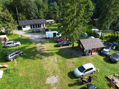 Widok z góry na trawiastą polanę, namioty, kampery oraz zabudowania obiektu Orłowa