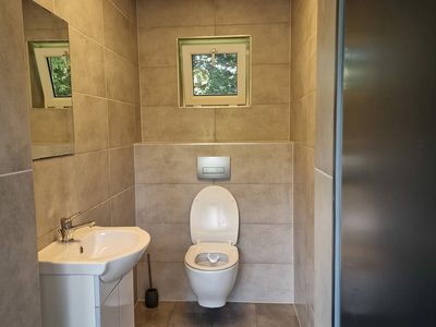 Czyste wnętrze sanitariatu z umywalką, lustrem i toaletą na obiekcie Orłowa